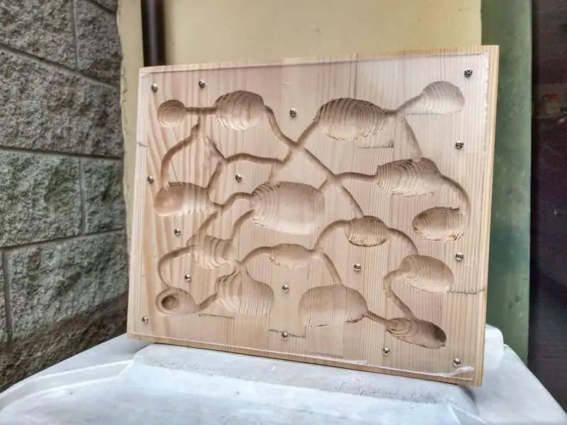 やすりがけで明るい木肌が出た木製のアリの巣。縁にネジ穴が開いている