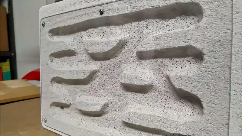 Close-up of a homemade Ytong nest showing its carved chambers through a clear plexiglass front panel